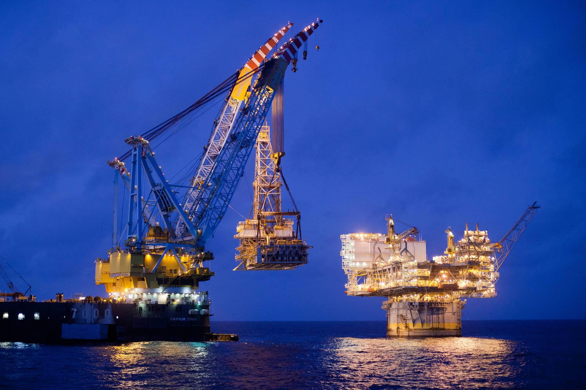 Heavy lift vessel and offshore platform at night.