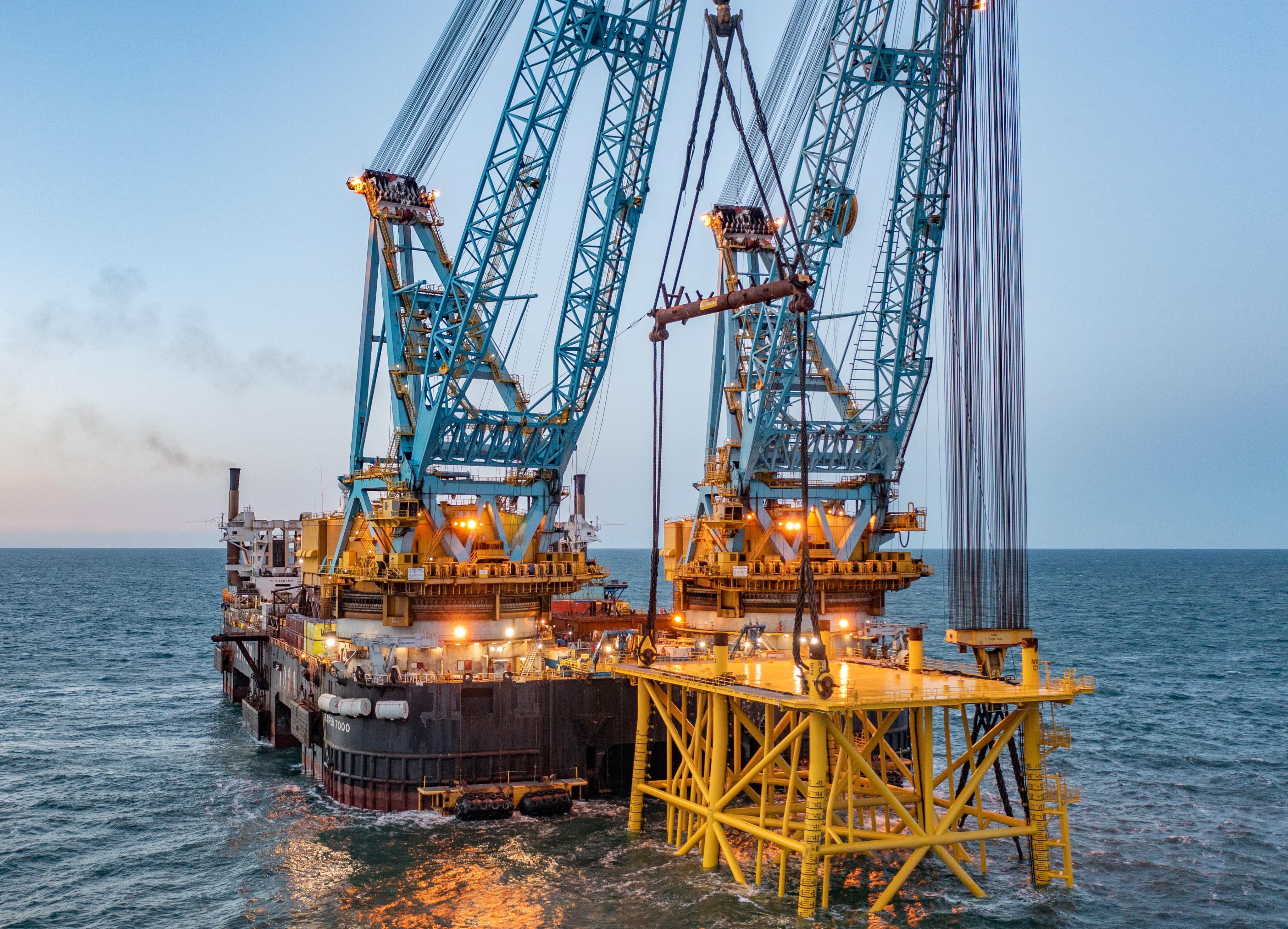 Marine cranes installing an offshore structure at sea